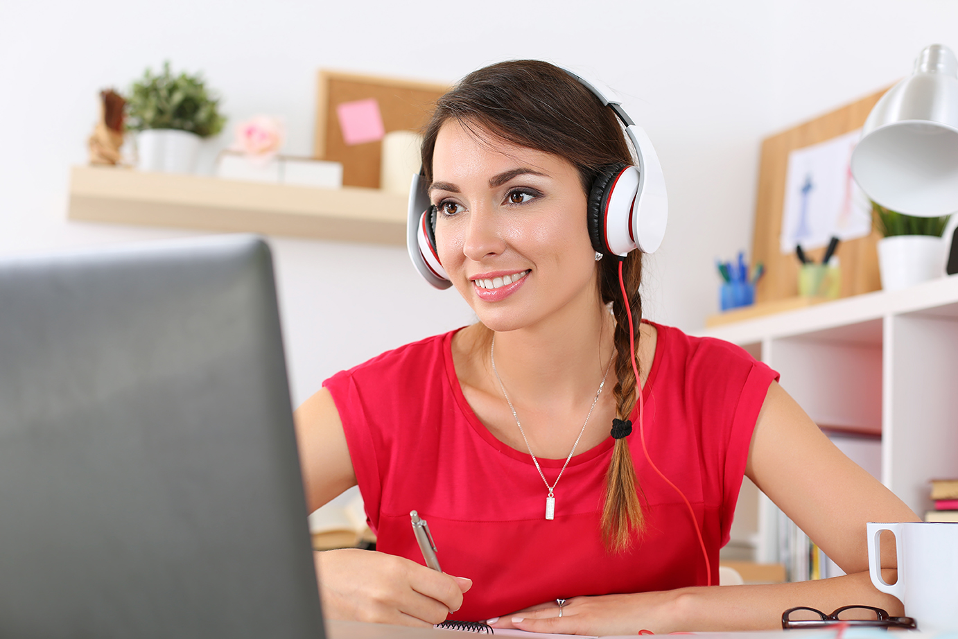 Modern study technology concept Beautiful smiling female student using online education service. Young woman looking in laptop display watching training course and listening it with headphones. Modern study technology concept