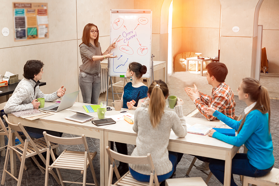 Young People listening Presentation of female Manager Young People listening Presentation of female Manager active Participants asking Questions in Meeting Room with wood Walls and Table using Flip Chart