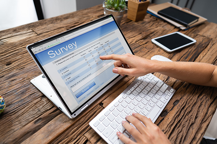 Cropped Image Of Businesswoman Giving Online Survey On Laptop At Office Desk