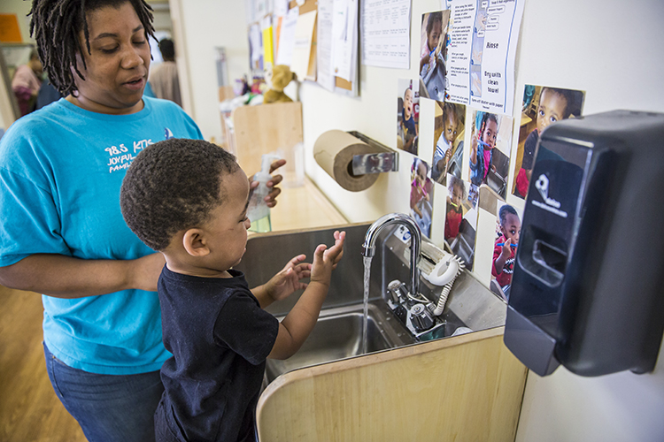 photo of child washing hands while provider watches