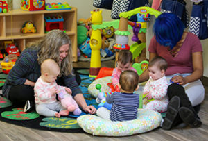 Four babies and two women playing