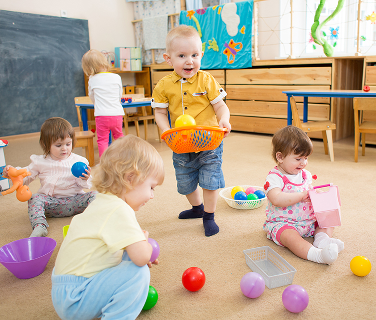 Group of kids playing with balls in kindergarten or day care centre